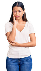 Young beautiful latin girl wearing casual white t shirt thinking looking tired and bored with depression problems with crossed arms.