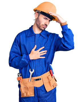 Young hispanic man wearing worker uniform touching forehead for illness and fever, flu and cold, virus sick