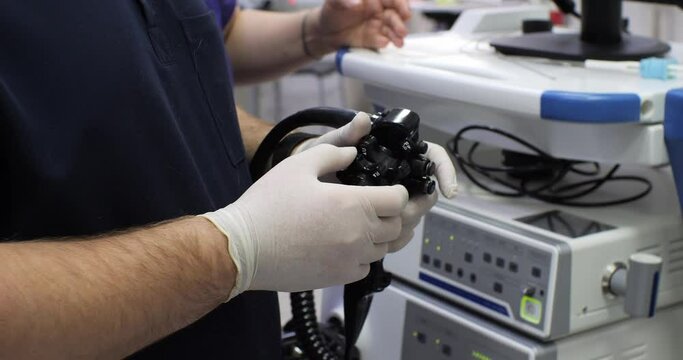 The doctor in the operating room holds a gastroscope in his hands and rotates the screws with his fingers. Close-up. The doctor performs a gastroscopic examination of the patient's stomach.