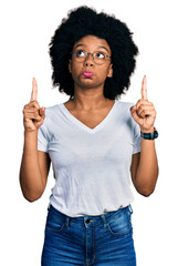 Young african american woman wearing casual white t shirt pointing up looking sad and upset, indicating direction with fingers, unhappy and depressed.