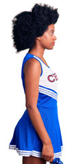 Fototapeta na wymiar Young african american woman wearing cheerleader uniform holding pompom looking to side, relax profile pose with natural face and confident smile.