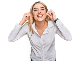 Young caucasian woman wearing casual clothes smiling pulling ears with fingers, funny gesture....