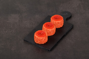 Vegan Tomato mousse cream appetizer of round cylindrical shape with tourbillon jelly on a top, on a serving board. Dark gray background