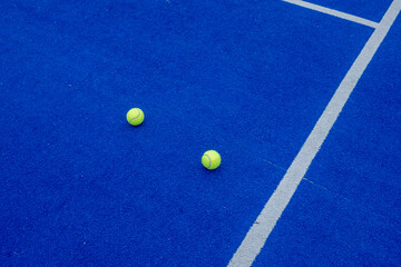 blue paddle tennis court, balls near the net and the center line