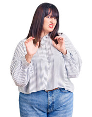 Young plus size woman wearing casual clothes disgusted expression, displeased and fearful doing disgust face because aversion reaction. with hands raised