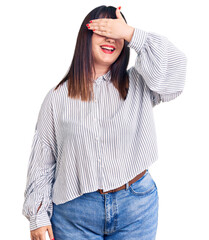 Young plus size woman wearing casual clothes smiling and laughing with hand on face covering eyes for surprise. blind concept.