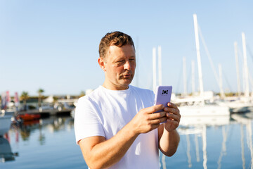 A man communicates on the phone against the background of yachts and a marina