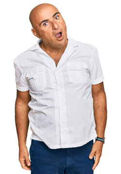 Mature middle east man with mustache wearing casual white shirt in shock face, looking skeptical and sarcastic, surprised with open mouth