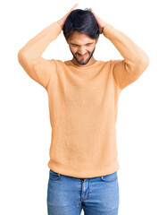 Handsome hispanic man wearing casual sweater suffering from headache desperate and stressed because pain and migraine. hands on head.