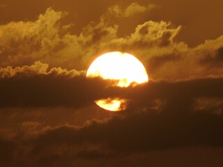Closeup of a burning round sun behind dense clouds