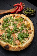 tasty pizza with cheese and vegetables on a wooden dark table
