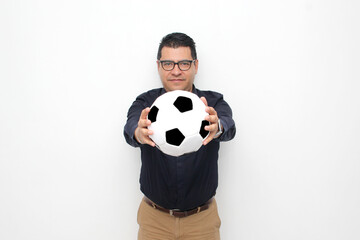 Latino adult office man plays with a soccer ball very excited that he is going to see the game and wants to see his team win