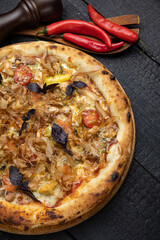 tasty pizza with cheese and vegetables on a wooden dark table
