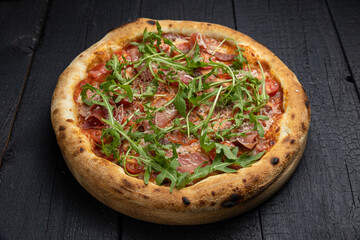 tasty pizza with cheese and vegetables on a wooden dark table
