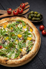 tasty pizza with cheese and vegetables on a wooden dark table
