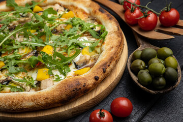 tasty pizza with cheese and vegetables on a wooden dark table
