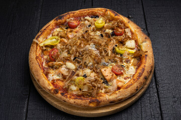 tasty pizza with cheese and vegetables on a wooden dark table
