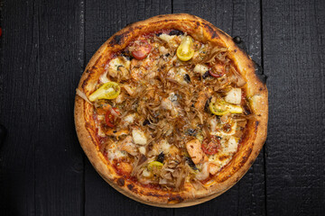 tasty pizza with cheese and vegetables on a wooden dark table
