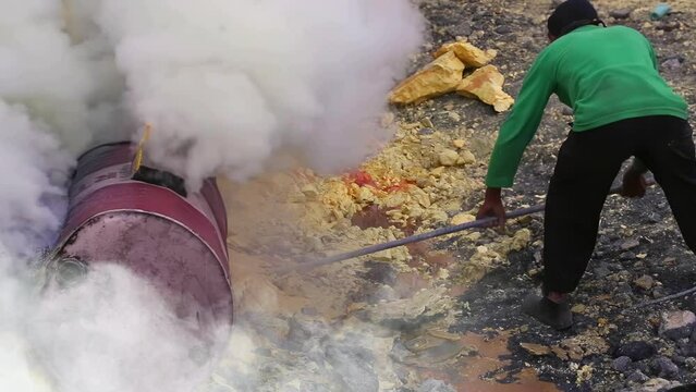 Close-up of worker extracting sulfur with scrap