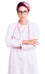 Young beautiful woman with pink hair wearing doctor uniform skeptic and nervous, disapproving expression on face with crossed arms. negative person.