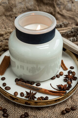 Aesthetic composition of candles, anise, cinnamon sticks and coffee beans on a background of burlap, decorated with dried flowers