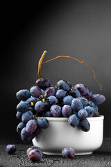 Blue grapes with water drops in a white plate vertical