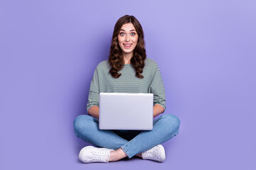 Naklejka premium Photo of astonished positive lady wear trendy stripe clothes sit floor impressed fast wifi connection isolated on purple color background