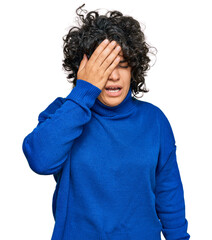 Young hispanic woman with curly hair wearing turtleneck sweater yawning tired covering half face, eye and mouth with hand. face hurts in pain.