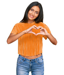 Young brunette arab woman wearing casual clothes smiling in love doing heart symbol shape with...