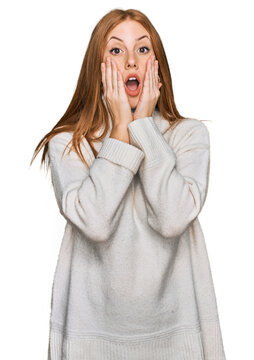 Young irish woman wearing casual winter sweater afraid and shocked, surprise and amazed expression with hands on face
