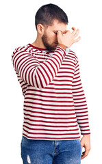 Obraz premium Young handsome man wearing striped sweater tired rubbing nose and eyes feeling fatigue and headache. stress and frustration concept.