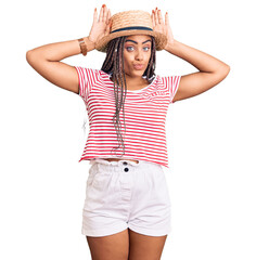 Young african american woman with braids wearing summer hat doing bunny ears gesture with hands palms looking cynical and skeptical. easter rabbit concept.