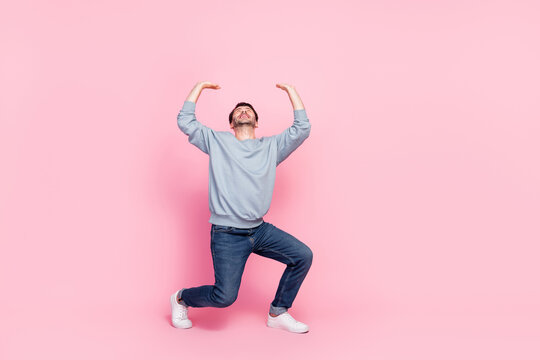 Full length photo of attractive young guy raise hands up carry heavy empty space dressed trendy blue look isolated on pink color background