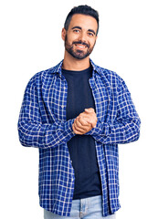 Young hispanic man wearing casual clothes with hands together and crossed fingers smiling relaxed...