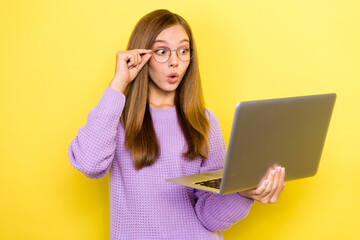 Photo of young teenager girl wear sweater pouted lips hold laptop shocked touch glasses advertisement video isolated on yellow color background