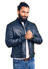 Young arab man wearing casual leather jacket with hands together and crossed fingers smiling relaxed and cheerful. success and optimistic