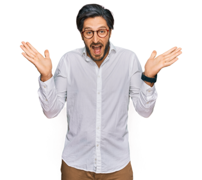 Young hispanic man wearing business shirt and glasses celebrating crazy and amazed for success with arms raised and open eyes screaming excited. winner concept