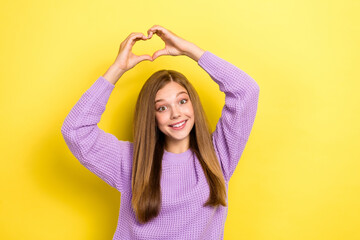 Photo of cheerful lady wear stylish violet sweater raise arm above head show heart figure empty space isolated on yellow color background