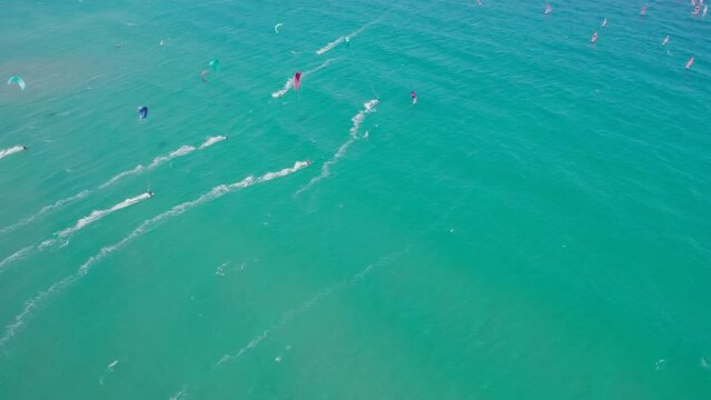 Drone view of lots of windsurfers and kite surfs sailing on the sea with blue sky and sea. Water sport with windsurfing and kitesurfing race