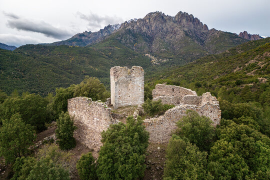 Aerial view of the ruins of Castellu di Seravalle in Corsica, a military fortress built in the 11th century on a hilltop with the village of Popolasca iwith les Aiguilles de Popolasca in the distance