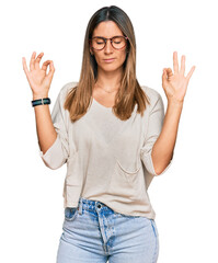 Young woman wearing casual clothes and glasses relax and smiling with eyes closed doing meditation...