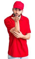 Young handsome man with beard wearing delivery uniform looking at the camera blowing a kiss with hand on air being lovely and sexy. love expression.