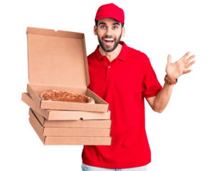 Young handsome man with beard wearing delivery uniform holding boxes with pizza celebrating victory with happy smile and winner expression with raised hands