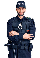 Young handsome man with beard wearing police uniform happy face smiling with crossed arms looking...