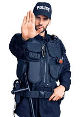 Young handsome man with beard wearing police uniform doing stop sing with palm of the hand. warning...