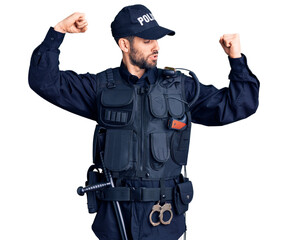 Young handsome man with beard wearing police uniform showing arms muscles smiling proud. fitness...