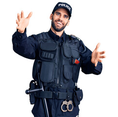 Young handsome man with beard wearing police uniform looking at the camera smiling with open arms for hug. cheerful expression embracing happiness.