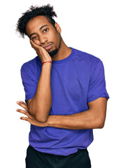 Young african american man with beard wearing casual purple t shirt thinking looking tired and bored with depression problems with crossed arms.