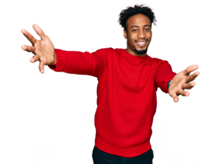 Young african american man with beard wearing casual winter sweater looking at the camera smiling with open arms for hug. cheerful expression embracing happiness.