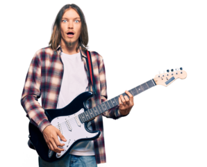 Handsome caucasian man with long hair playing electric guitar scared and amazed with open mouth for surprise, disbelief face